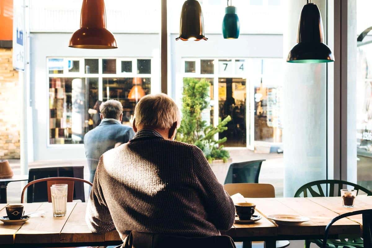 Dos personas sentadas junto al ventanal de una cafetería.